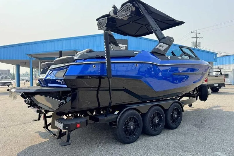 Slide: The Image of 2027 MasterCraft X23 boat on trailer, vibrant blue and black design, parked outdoors. - 7