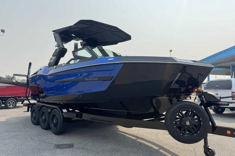 Slide: The Image of 2027 MasterCraft X23 boat on trailer, featuring sleek blue and black design. - 2