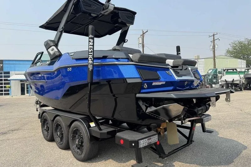Slide: The Image of 2027 MasterCraft X23 boat in blue on a trailer, parked outdoors. - 12