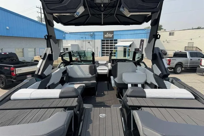 Slide: The Image of 2027 MasterCraft X23 boat interior with modern seating and sleek design in a dealership lot. - 13