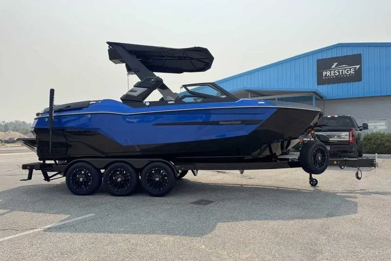 Slide: The Image of 2027 MasterCraft X23 boat on trailer outside Prestige Water Sports building. - 6