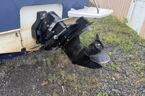 Slide: The Image of 2004 Bayliner 194 boat stern drive on gravel, showcasing propeller and outboard motor. - 3