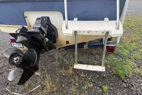 Slide: The Image of 2004 Bayliner 194 boat stern with propeller and swim ladder on gravel surface. - 4