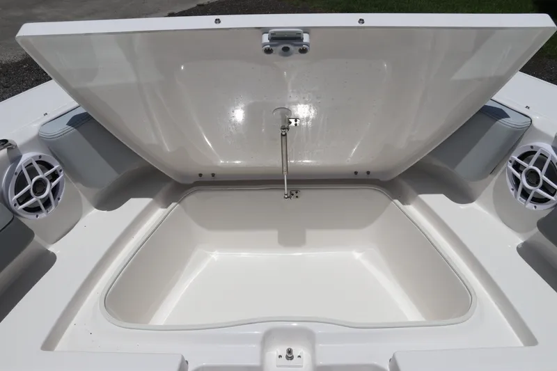Slide: The Image of 2027 Robalo R207 Dual Console boat storage compartment with open lid and speakers. - 36