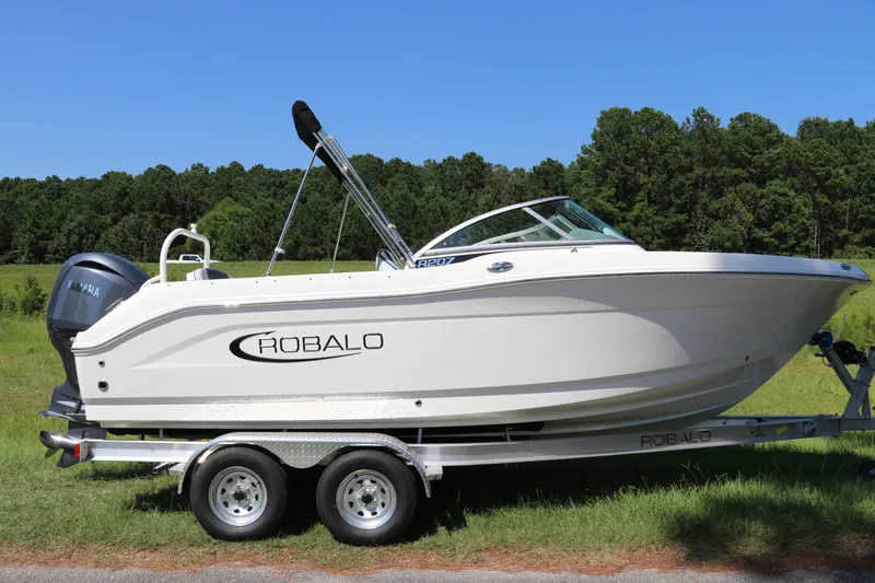The Image of 2027 Robalo R207 Dual Console boat on trailer, parked in grassy area. - 0