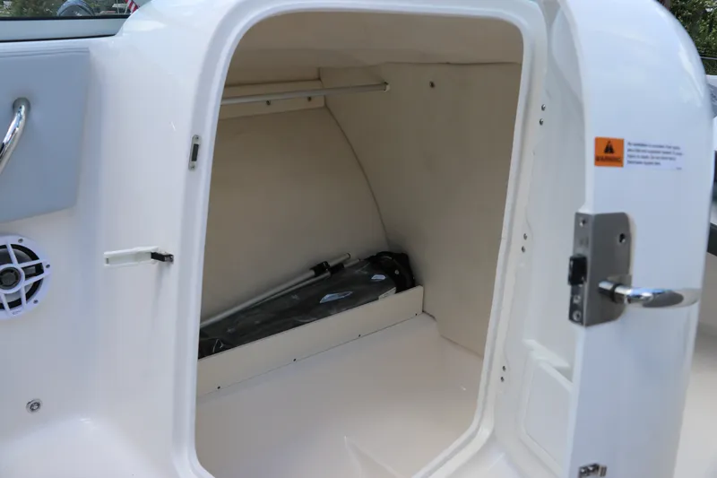 Slide: The Image of Storage compartment in 2027 Robalo R207 Dual Console boat, featuring secure latch and interior space. - 23