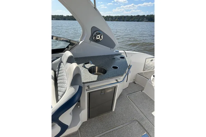 Slide: The Image of 2013 Chaparral 327 SSX boat interior with seating and kitchenette on a lake. - 39