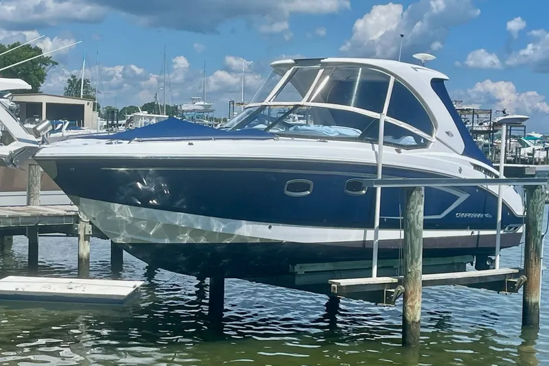Slide: The Image of 2013 Chaparral 327 SSX boat docked, featuring sleek design and blue hull under a sunny sky. - 50