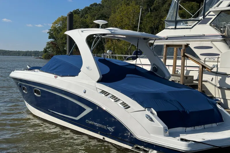 Slide: The Image of 2013 Chaparral 327 SSX boat docked on a calm lake with blue covers. - 0