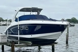 Slide: The Image of 2013 Chaparral 327 SSX boat docked on a lift by the water. - 2