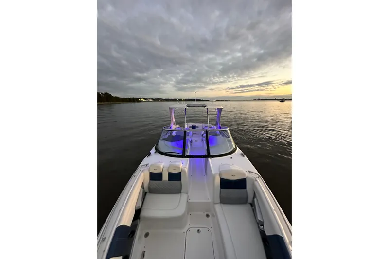 Slide: The Image of 2013 Chaparral 327 SSX boat on calm water at sunset with blue interior lights. - 28