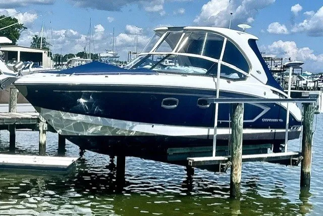 The Image of 2013 Chaparral 327 SSX boat docked, featuring sleek design and blue hull under a sunny sky. - 0