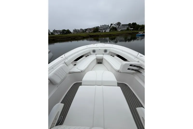 Slide: The Image of 2026 Tidewater 320 CC Adventure boat interior with white seating, docked near waterfront homes. - 22