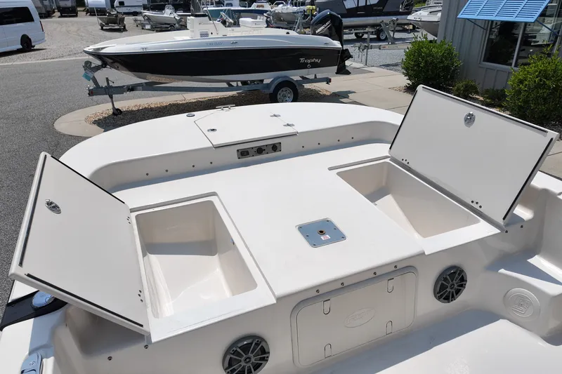 Slide: The Image of 2027 Carolina Skiff 21LS boat with open storage compartments, docked at a marina. - 15