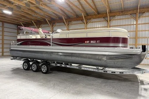 The Image of 2004 Bennington 2575 pontoon boat on trailer in a spacious indoor storage facility. - 1