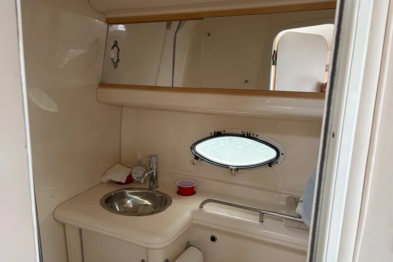 Slide: The Image of 2001 Larson Cabrio 330 boat bathroom with sink, porthole, and storage shelf. - 14