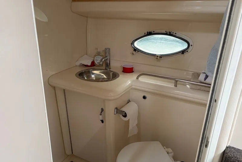 Slide: The Image of 2001 Larson Cabrio 330 boat bathroom with sink, toilet, and porthole window. - 15