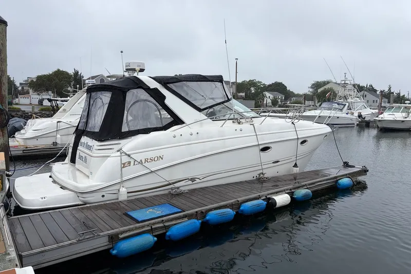The Image of 2001 Larson Cabrio 330 boat docked at marina, overcast sky, calm water. - 0