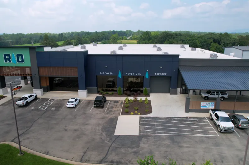 Slide: The Image of A modern building with large windows and a parking lot in front. It is surrounded by trees. - 9