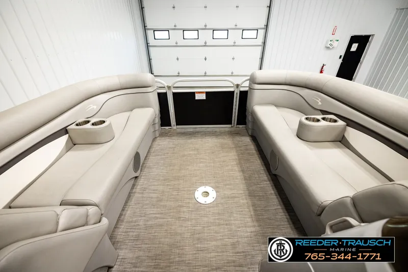 Slide: The Image of 2021 Bennington SVSR boat interior with beige seating and cup holders in a showroom. - 19