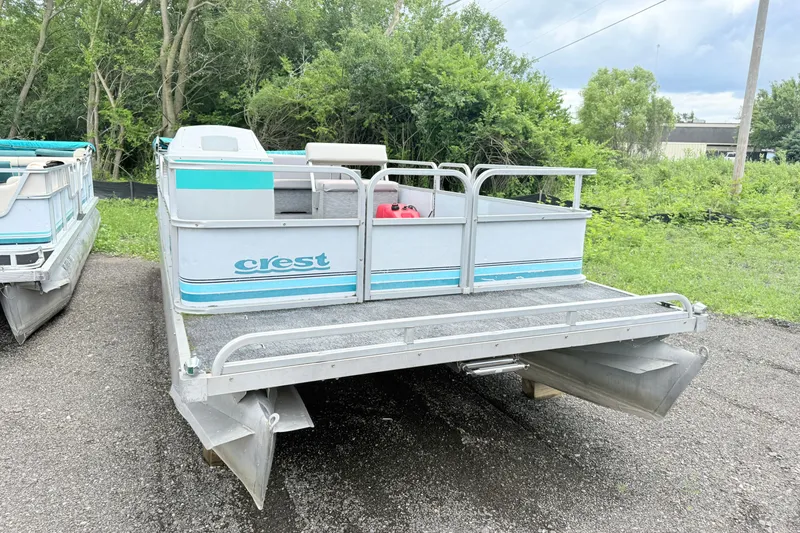 Slide: The Image of 1993 Crest Sport pontoon boat parked on gravel, surrounded by greenery. - 2