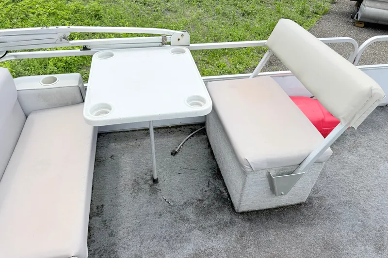 Slide: The Image of 1993 Crest Sport boat interior with white seating and table, set against a grassy background. - 8