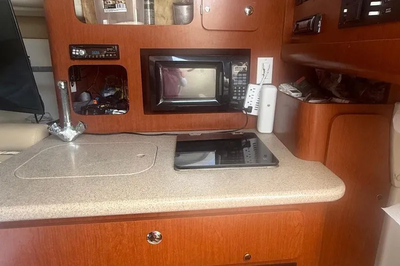 Slide: The Image of 2007 Pro-Line 32 Express boat interior with microwave, sink, and wooden cabinetry. - 3