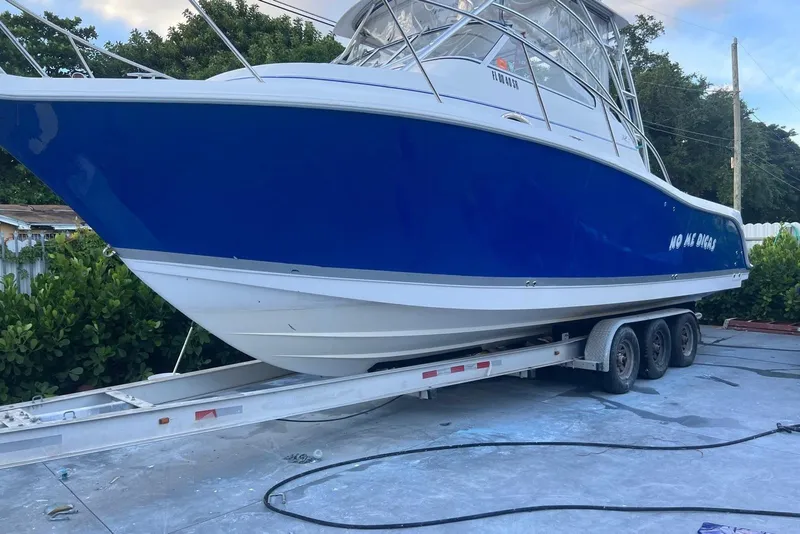 The Image of 2007 Pro-Line 32 Express boat on trailer, blue and white design, parked outdoors. - 0