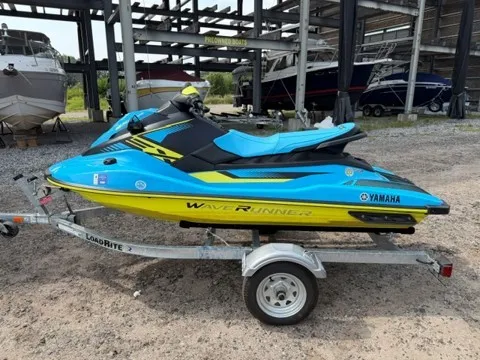 The Image of A blue and yellow 2023 Yamaha EX WaveRunner sits on a trailer in a storage area. - 1