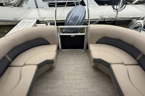 Slide: The Image of 2024 Bennington 22LSR pontoon boat interior with beige seating at dock. - 3
