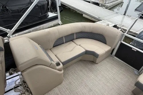 Slide: The Image of 2024 Bennington 22LSR pontoon boat with beige seating and cup holder, docked at marina. - 4