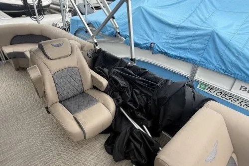 Slide: The Image of 2024 Bennington 22LSR pontoon boat with beige seating and blue cover. - 9