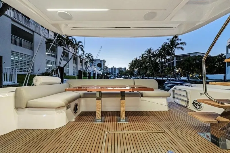 Slide: The Image of Luxurious 2020 Prestige 590 yacht deck with elegant seating and wooden table, docked at sunset. - 13