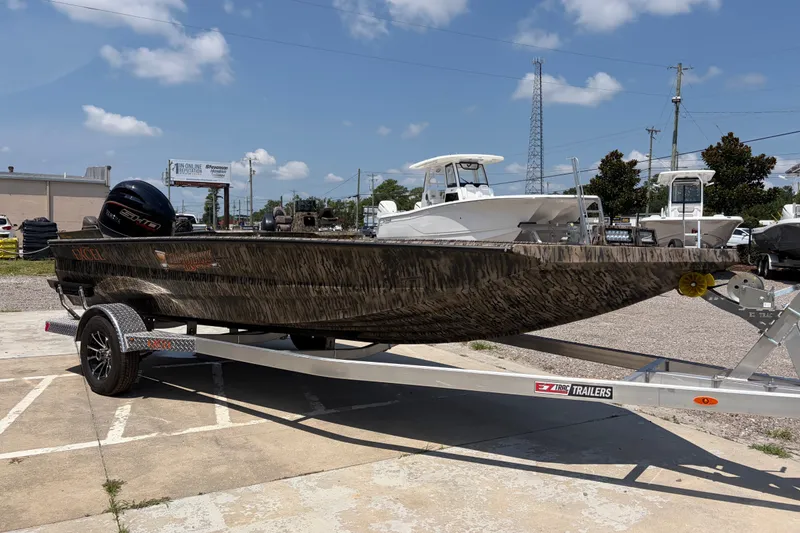 Slide: The Image of 2026 Excel 183 Tomahawk boat on trailer, parked outdoors under blue sky. - 6