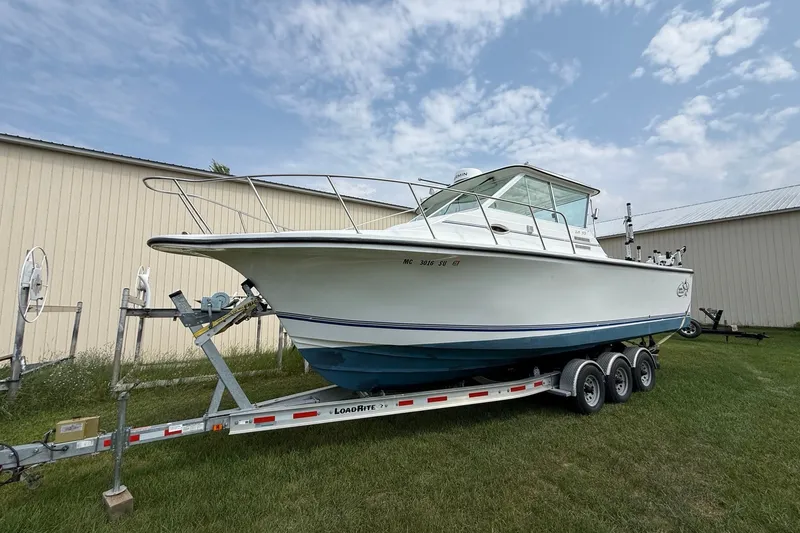 The Image of 2006 Baha Cruiser 299 SF boat on trailer, parked on grass near a building. - 1