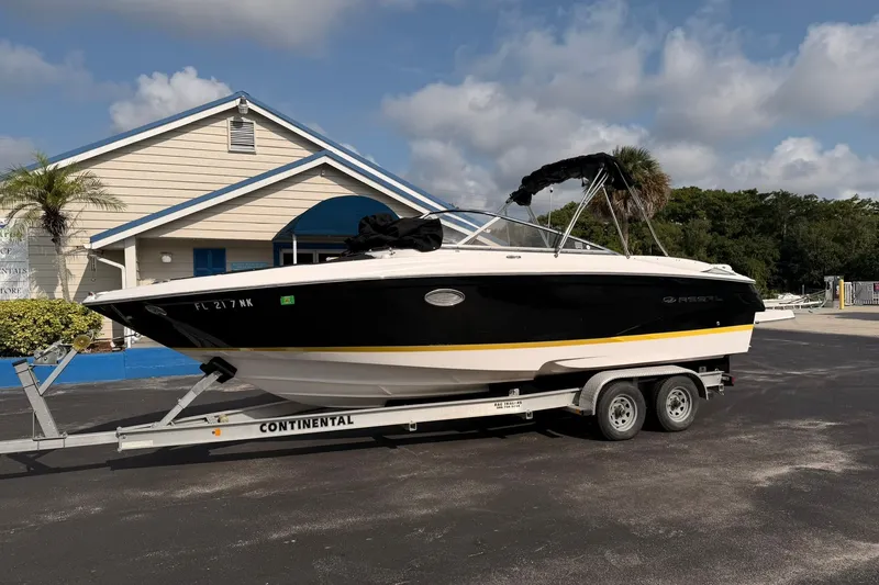 Slide: The Image of 2007 Regal 2700 Bowrider boat on trailer, parked near a building under a cloudy sky. - 5