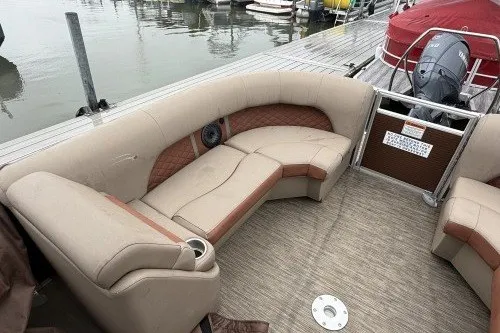 Slide: The Image of 2022 Bennington 22LSR pontoon boat interior with beige seating and docked at a marina. - 8