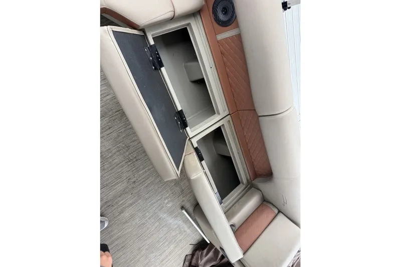 Slide: The Image of Open storage compartment on a 2022 Bennington 22LSR boat with beige and tan seating. - 11