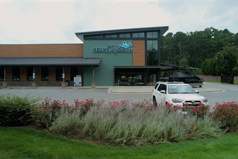 The Image of A modern building with a white SUV in the foreground and a boat in the background. - 1