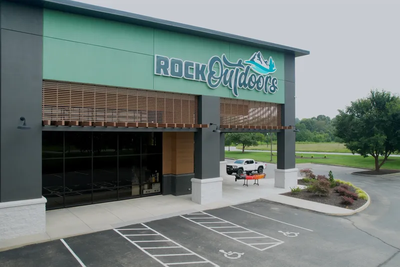 Slide: The Image of Rock Outdoors store with modern design and outdoor parking area. - 2