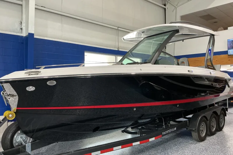 The Image of 2027 Monterey Elite 27 SD boat on trailer in showroom, featuring sleek black and white design. - 1
