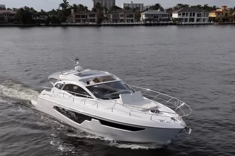 Slide: The Image of 2024 Sessa Marine C44 Cruiser navigating a serene waterfront with luxury homes in the background. - 13