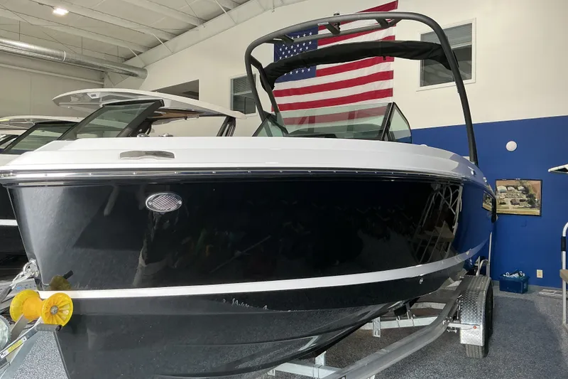 The Image of 2027 Monterey Elite 25 SD boat in showroom, American flag backdrop. - 1