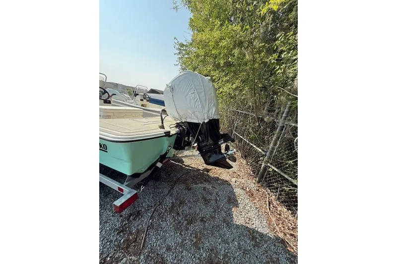Slide: The Image of 2025 Mako Pro Skiff 17 CC boat on trailer, covered motor, parked on gravel. - 13