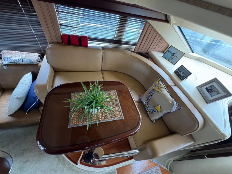 Slide: The Image of The interior cabin of a 2007 Sea Ray 44 Sedan Bridge features an elegant seating area with a wooden table and decorative pillows. - 6