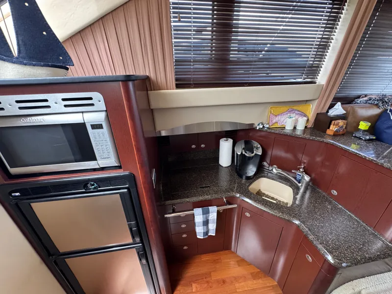 Slide: The Image of The 2007 Sea Ray 44 Sedan Bridge kitchen features a microwave, refrigerator, and sink. - 8
