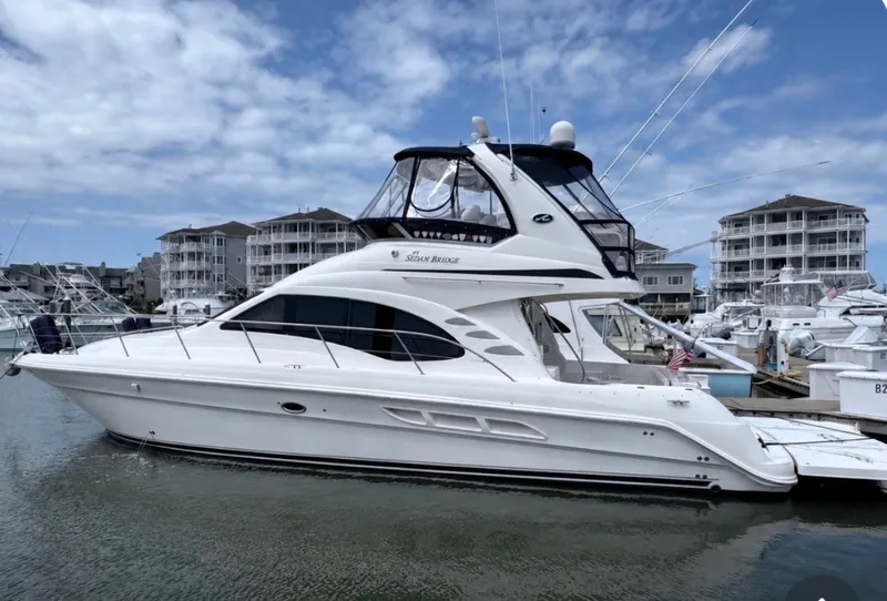 The Image of A 2007 Sea Ray 44 Sedan Bridge docked in a marina. White yacht with two decks and cabin. - 0
