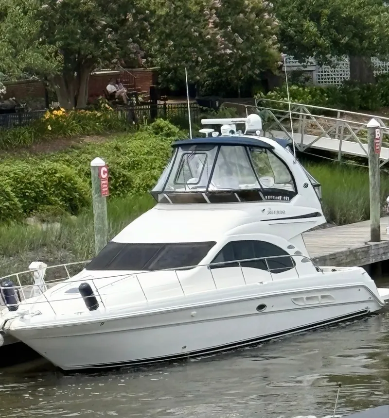 The Image of 2007 Sea Ray 44 Sedan Bridge at a calm dock with lush greenery in the background. - 0