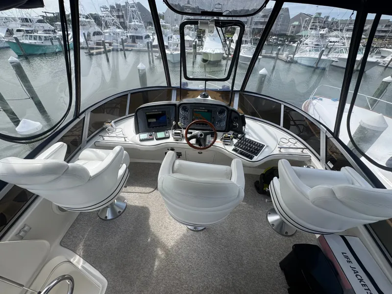 Slide: The Image of The cockpit of a 2007 Sea Ray 44 Sedan Bridge with three white seats and a steering wheel. - 18