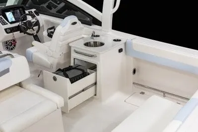 Slide: The Image of 2026 Robalo R257 Dual Console interior with helm, sink, and storage drawers. - 5